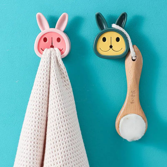 A set of bathroom towel and plug organizers in the form of bunny and bear faces, attached to a blue wall.