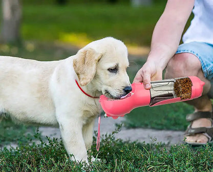 A dog being fed from a pink portable pet feeder.